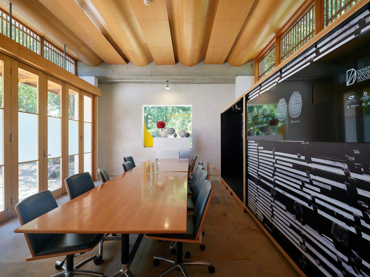 Sala de reunião com mesa longa de madeira e janelas
