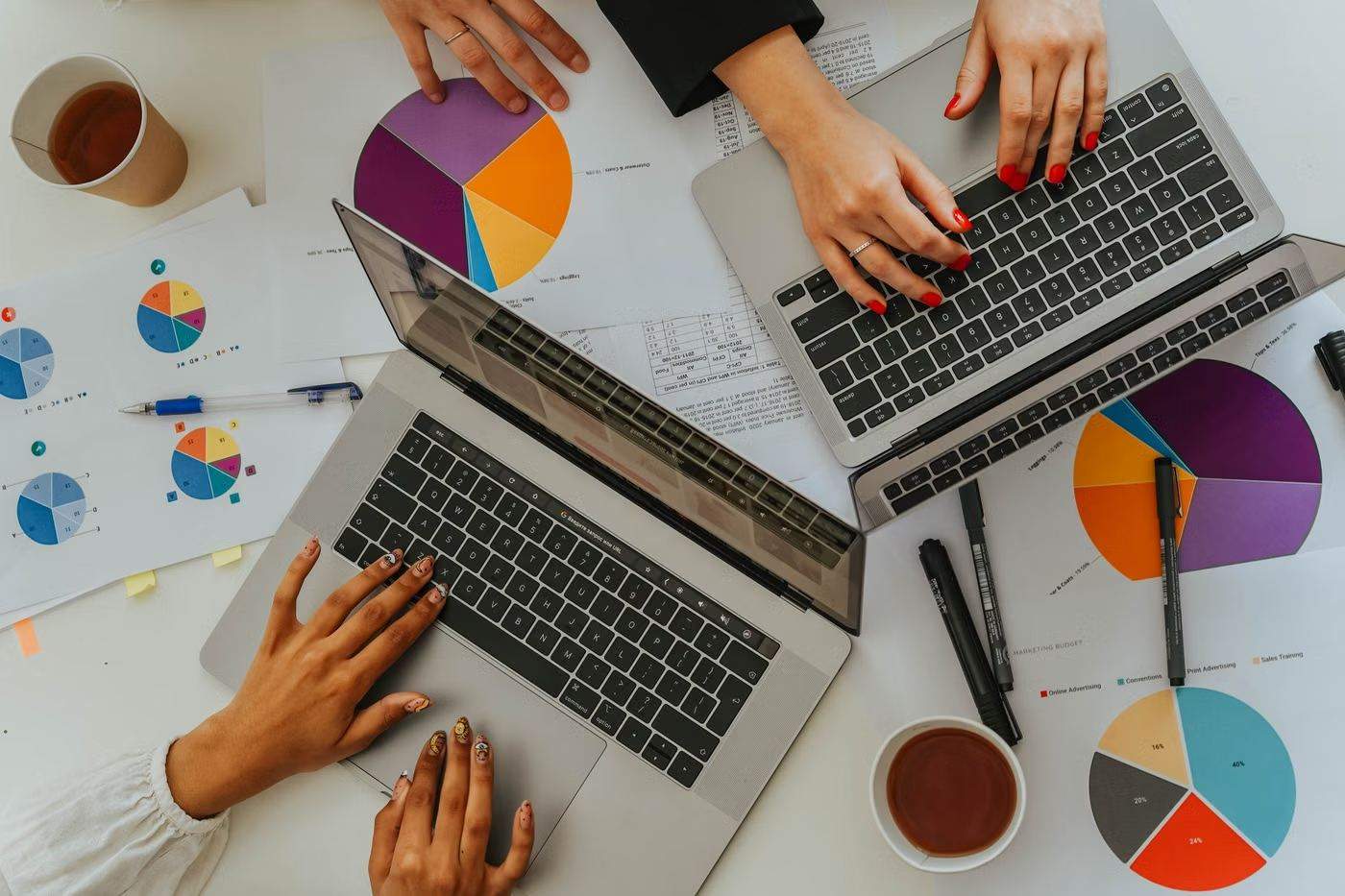Vista de cima de um time analisando gráficos e indicadores em notebooks